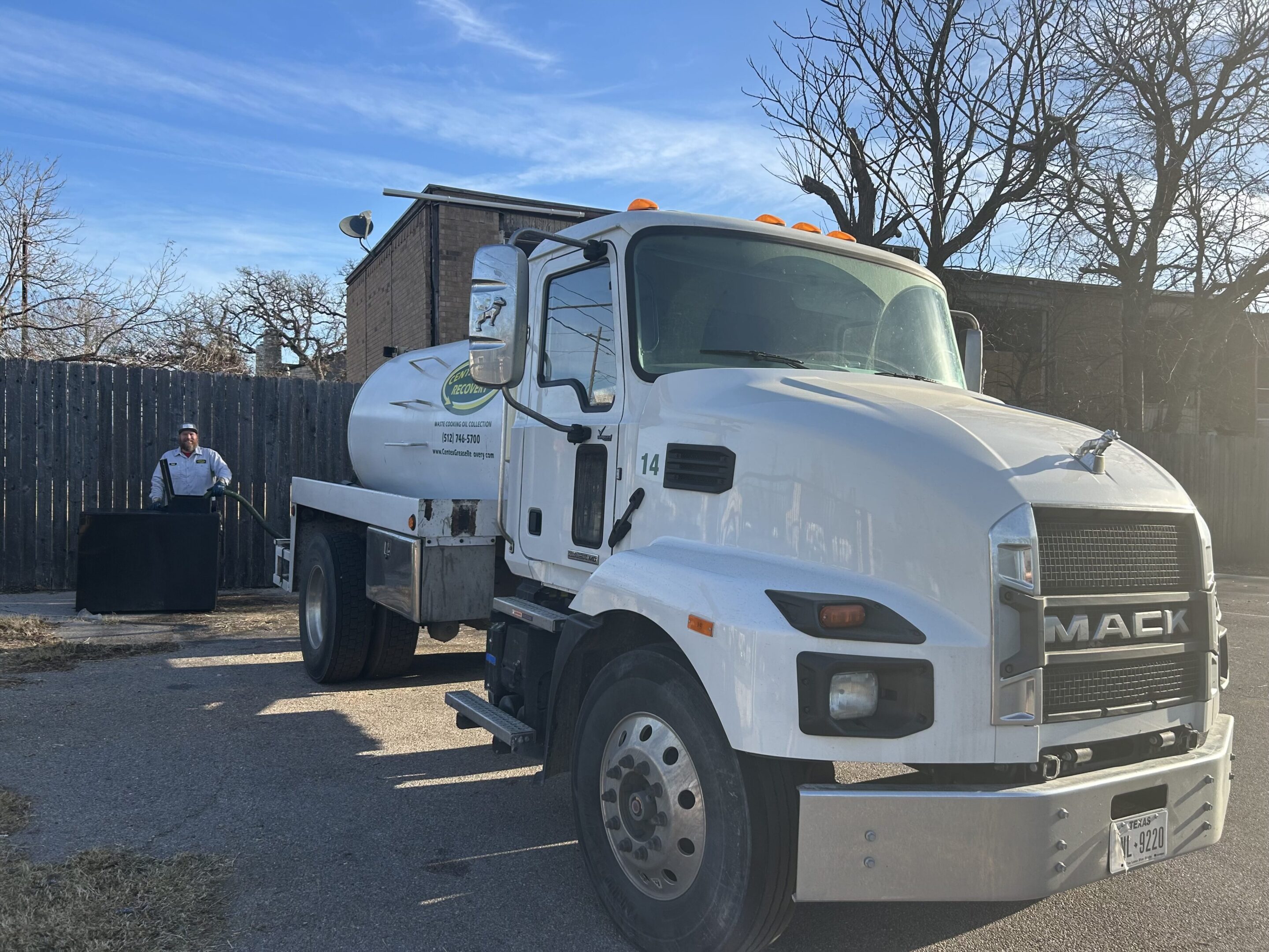 A white tanker truck parked outdoors on a sunny day.